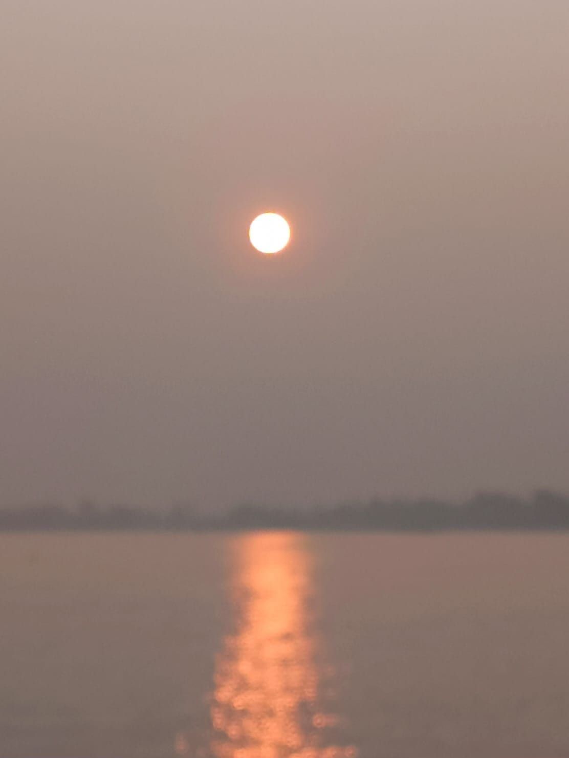 Sun rising through morning haze over Vembanad Lake
